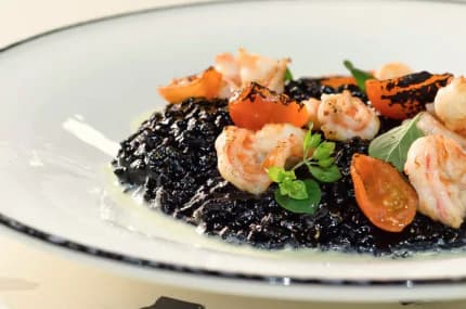 Risotto integrale mantecato al campari con gambero rosso, nero di seppia ciauscolo croccante e germogli di pisello
